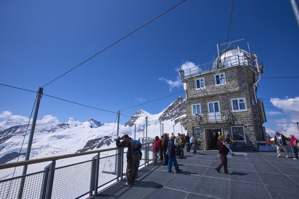 Jungfraujoch observation deck near the snowy peaks of the Mönch and Jungfrau mountains.